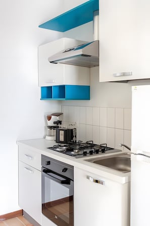Una cucina moderna con mobili bianchi, piano cottura a gas, macchina da caffè e forno integrato.