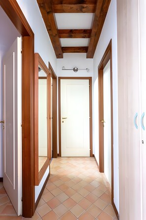 A hallway with wooden doors, a tiled floor, and a wooden ceiling.