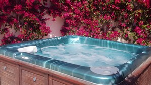 A hot tub with a wooden exterior and a glass top, surrounded by pink flowering plants. - Villa 'Ensueno with Private Pool' with Private Pool, Wi-Fi and Air Conditioning (Mazarrón)