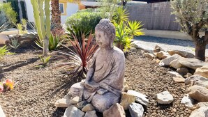 A statue of a seated figure in a garden setting with rocks and plants. - Villa 'Ensueno with Private Pool' with Private Pool, Wi-Fi and Air Conditioning (Mazarrón)