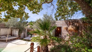Un espace extérieur rustique doté d’une terrasse en bois, d’un palmier et d’une structure à toit de chaume.