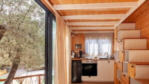 Une cuisine de taille réduite, dotée de meubles en bois, d’un lave-vaisselle et d’une fenêtre donnant sur un arbre.