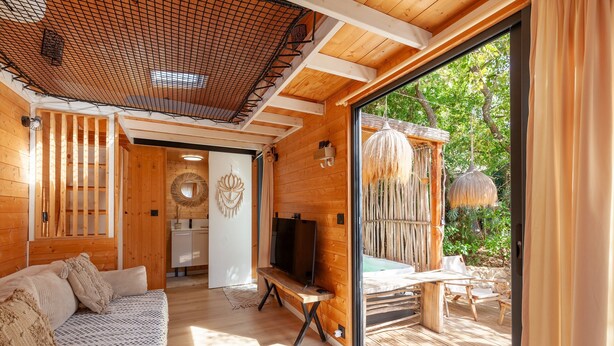 Un intérieur en bois avec un canapé, un téléviseur et une vue sur l’extérieur.