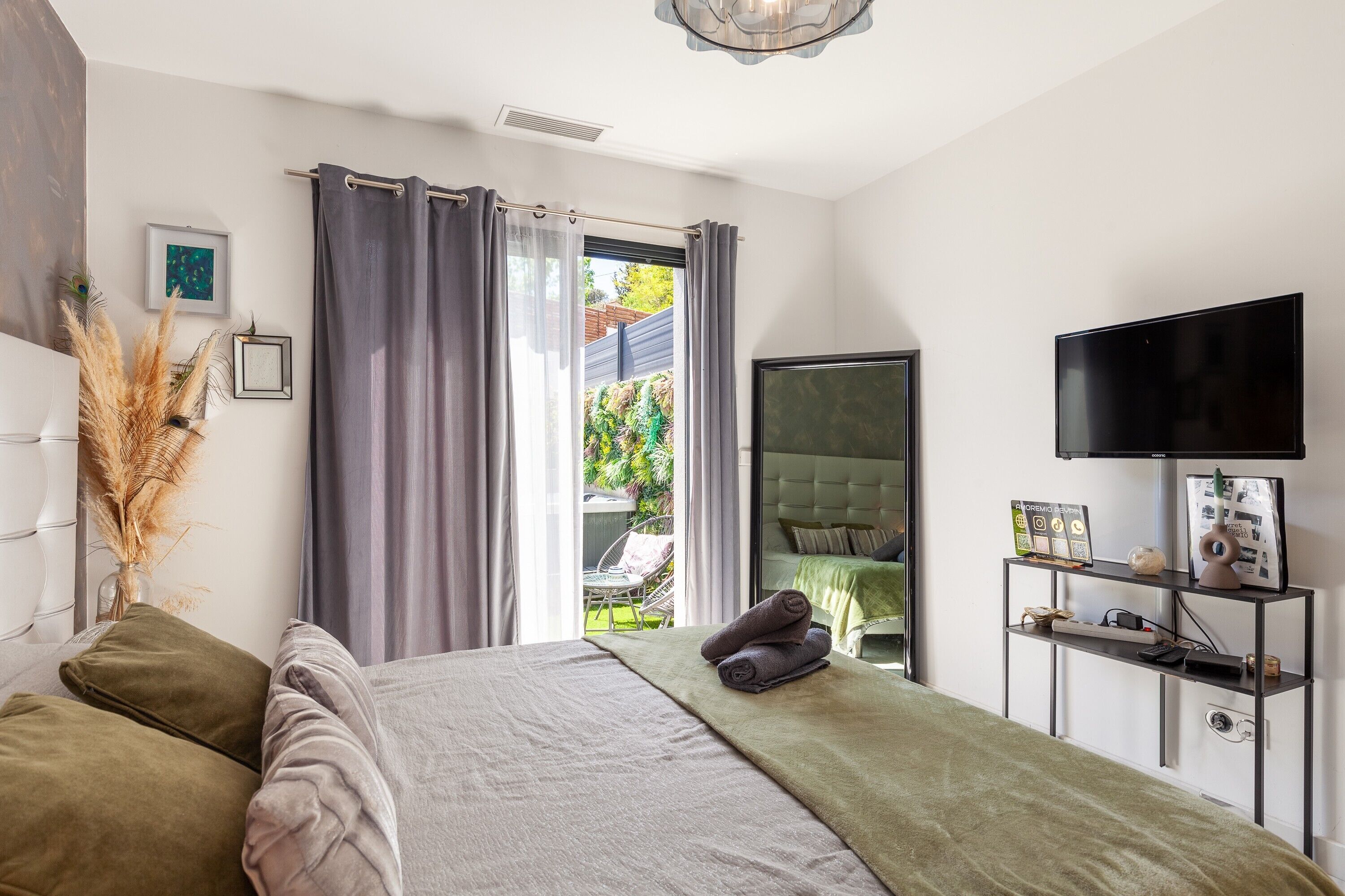 Une chambre à coucher avec un lit, une télévision, une table de chevet et une fenêtre avec des rideaux.