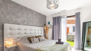 A bedroom with a large bed, a bedside table with a lamp, a view of the outside, and a modern chandelier. - Apartment 'Phuket' with Mountain View, Wi-Fi and Air Conditioning (Peypin)