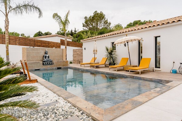 Una piscina amb gandules, una estàtua de Buda i una pérgola.