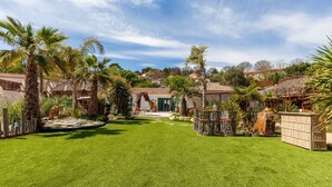 A well-maintained garden with palm trees, a thatched-roof structure, and a clear sky. - Apartment 'Phuket' with Mountain View, Wi-Fi and Air Conditioning (Peypin)