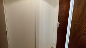 Una habitación con puerta de madera, un armario blanco y una lámpara.