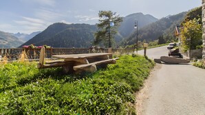 Vista panorámica de la montaña con un banco de madera, un muro de piedra y una carretera.