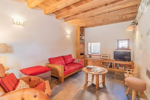 Un salón acogedor con un sofá rojo, muebles de madera, un televisor y una estantería.