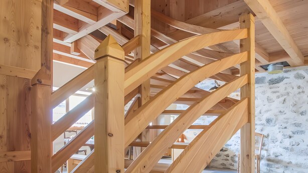 Una escalera de madera con un muro de piedra al fondo.