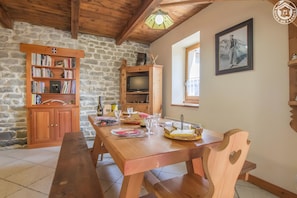 A wooden dining table with chairs, a bookshelf, a television, and a framed picture on the wall. - Apartment 'Le Blanchon' with Mountain View and Wi-Fi (Montricher-Albanne)