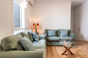 A living room with two green sofas, a glass coffee table, and a lamp. - Bright Spacious Apartment with Private Terrace & Air Conditioning in Seville (Seville)