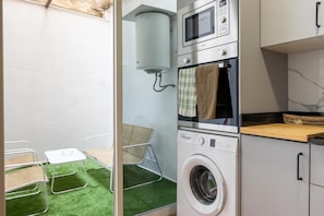 A compact laundry room with a washing machine, dryer, microwave, and a small table with chairs.