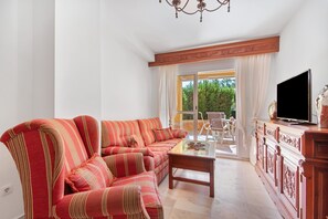 Un salon comprenant un canapé, un téléviseur et une table basse en verre.