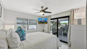 A bedroom with a bed, a ceiling fan, a TV, and a balcony with a view of the mountains. - 🏖️ Coastal Luxury Retreat | Private Pool & Spa • Walk to Vanderbilt Beach • Naples Park Gem (Naples)