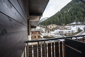Ein Holzbalkon mit Blick auf eine Berglandschaft und mehrere Gebäude.