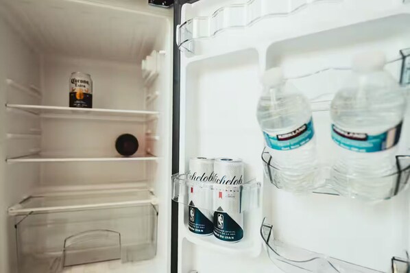 Ein offener Kühlschrank mit Regalen, auf denen eine Corona-Bierdose, zwei Wasserflaschen und eine Packung Michelob Ultra Bier stehen.