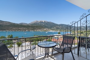 A balcony with a view of a lake, mountains, and boats.
