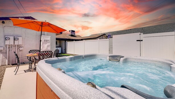 Un jacuzzi con revestimiento de piedra, una mesa de patio y una sombrilla.