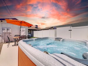 A hot tub with a stone exterior, a patio table, and an umbrella.