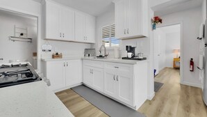 Una cocina moderna con armarios blancos, estufa integrada y cafetera.