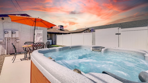 Un jacuzzi con revestimiento de piedra, una mesa de patio y una sombrilla.