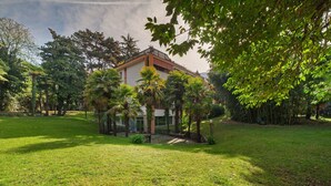 A modern building with a flat roof, surrounded by a well-maintained lawn and various trees. - Apartment 'Modern Park' with Shared Garden, Balcony and Wi-Fi (Meran)