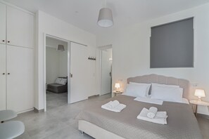 Een moderne hotelkamer met een bed, nachtkastjes, een kledingkast en een badkamer zichtbaar door een geopende deur.