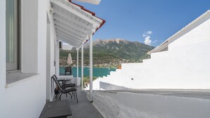 A white building with a balcony, outdoor seating, and a view of mountains. - Studio Apartment 'Chakalaka -  with Sofa Bed 4' with Mountain View, Wi-Fi and Air Conditioning (Leykada)