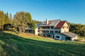 A large two-story house with a sloped roof, a chimney, and a covered porch. - Cottage 'Jean Macé' with Mountain View and Wi-Fi (Haut Valromey)