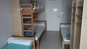 Un dormitorio con literas, una puerta con un adhesivo y un armario.