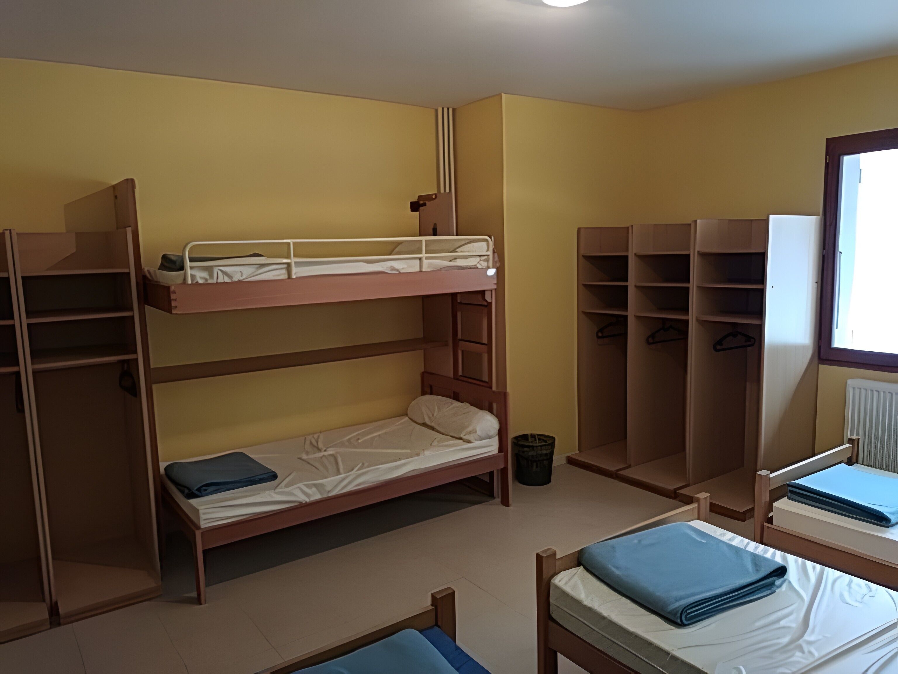 Een slaapkamer met een stapelbed, bureau, planken en een radiator.
