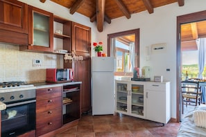 A kitchen with wooden cabinets, a stove, a microwave, a refrigerator, and a window with a view.