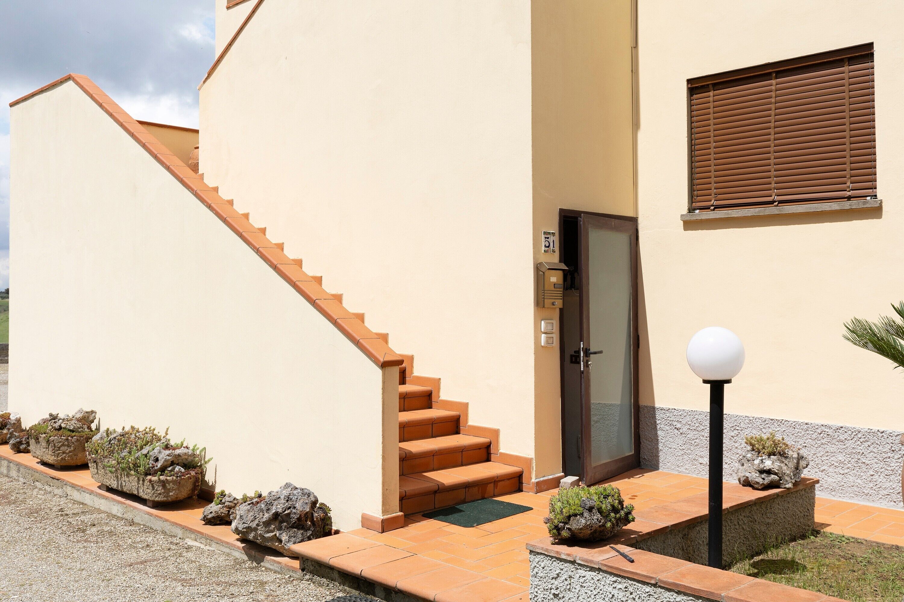 Un bâtiment moderne doté d’un escalier, d’une porte et d’une fenêtre avec des stores.