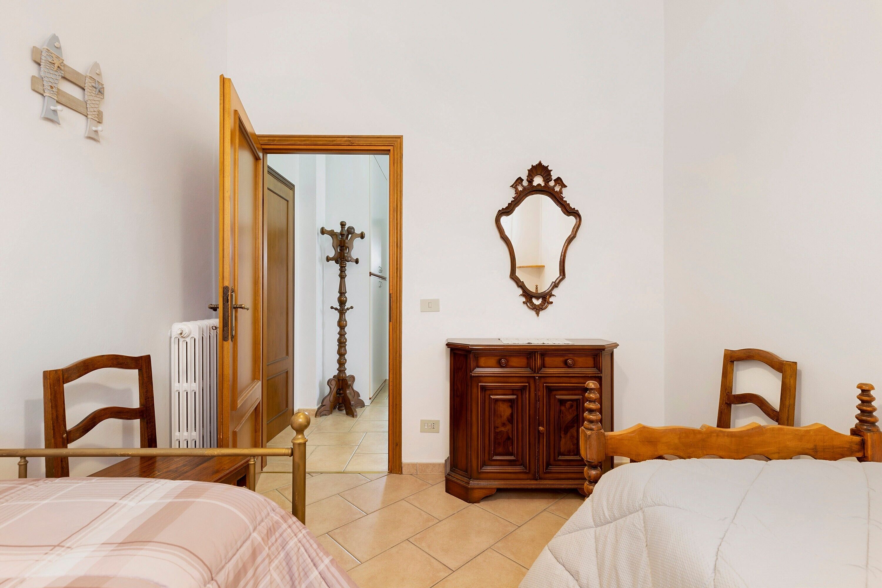 Une chambre à coucher avec un lit en bois, une commode en bois, un miroir et un radiateur.