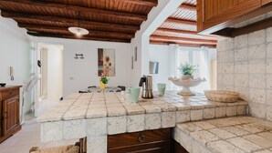 A kitchen with a stone countertop, wooden cabinets, and a ceiling with exposed beams. - One-Bedroom Apartment with Private Terrace and Air Conditioning (Marinella di Selinunte)