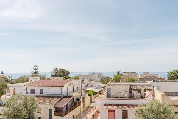 A coastal residential area with buildings, some with balconies, and a view of the sea.