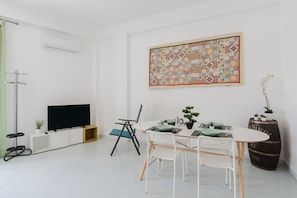 Un salon moderne doté d’un téléviseur à écran plat, d’une table à manger avec des chaises, d’une courtepointe décorative et d’un grand tonneau.