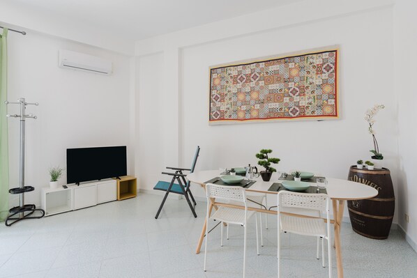 Un salon moderne doté d’un téléviseur à écran plat, d’une table à manger avec des chaises, d’une courtepointe décorative et d’un grand tonneau.