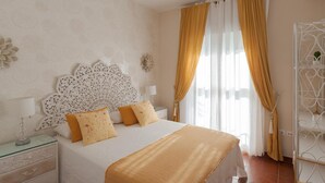 A bedroom with a bed, curtains, a decorative headboard, and a nightstand.