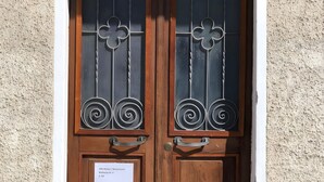 A double wooden door with decorative metal grilles and a sign indicating a villa apartment.