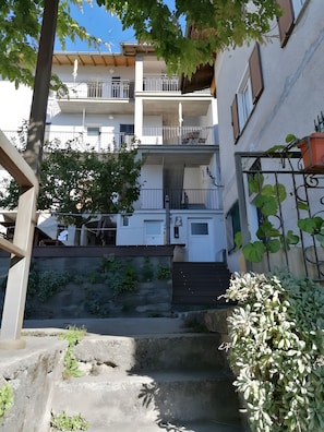 Un immeuble résidentiel à plusieurs étages, doté de balcons, d’un escalier et d’un petit jardin.