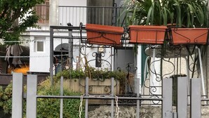 A sign for Villa Wetzel with a metal gate and a view of a building with a stone wall and a blue barrel.