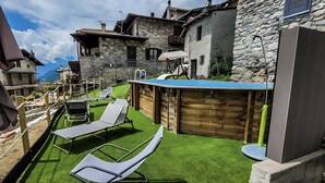 Un edificio de piedra con piscina, sillones de descanso y una terraza de madera.