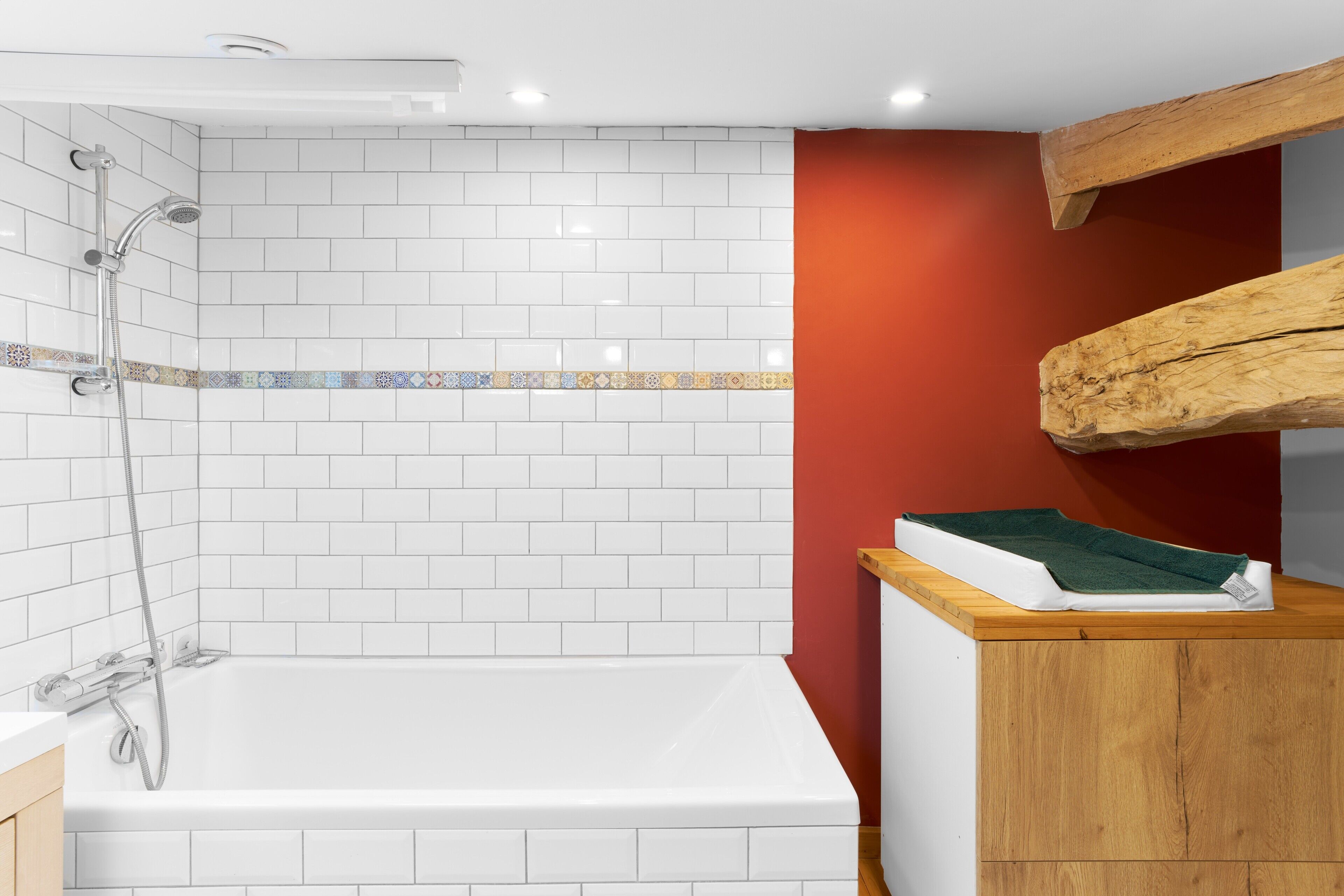 A bathroom with a white bathtub, a shower, and a wooden vanity.