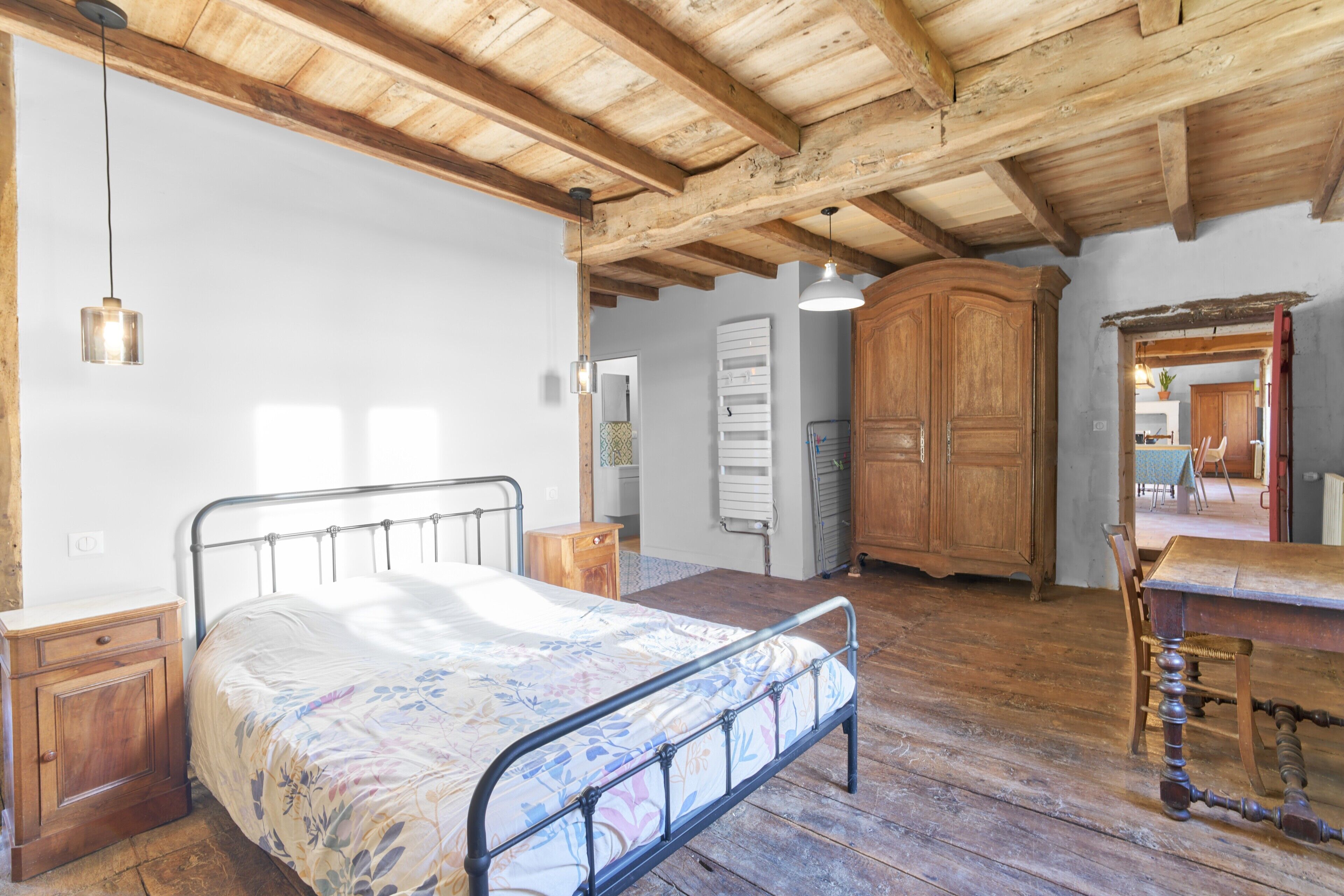 Ein rustikales Zimmer mit Bett, Holzmöbeln und sichtbaren Holzbalken.