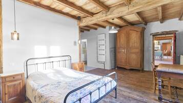 Ein rustikales Zimmer mit Bett, Holzmöbeln und sichtbaren Holzbalken.