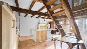 A kitchen with wooden beams, a central island, and a dining table. - Traditional and Organic Gîte in the Tude Valley – Nature, Comfort, and Relaxation (Montboyer)