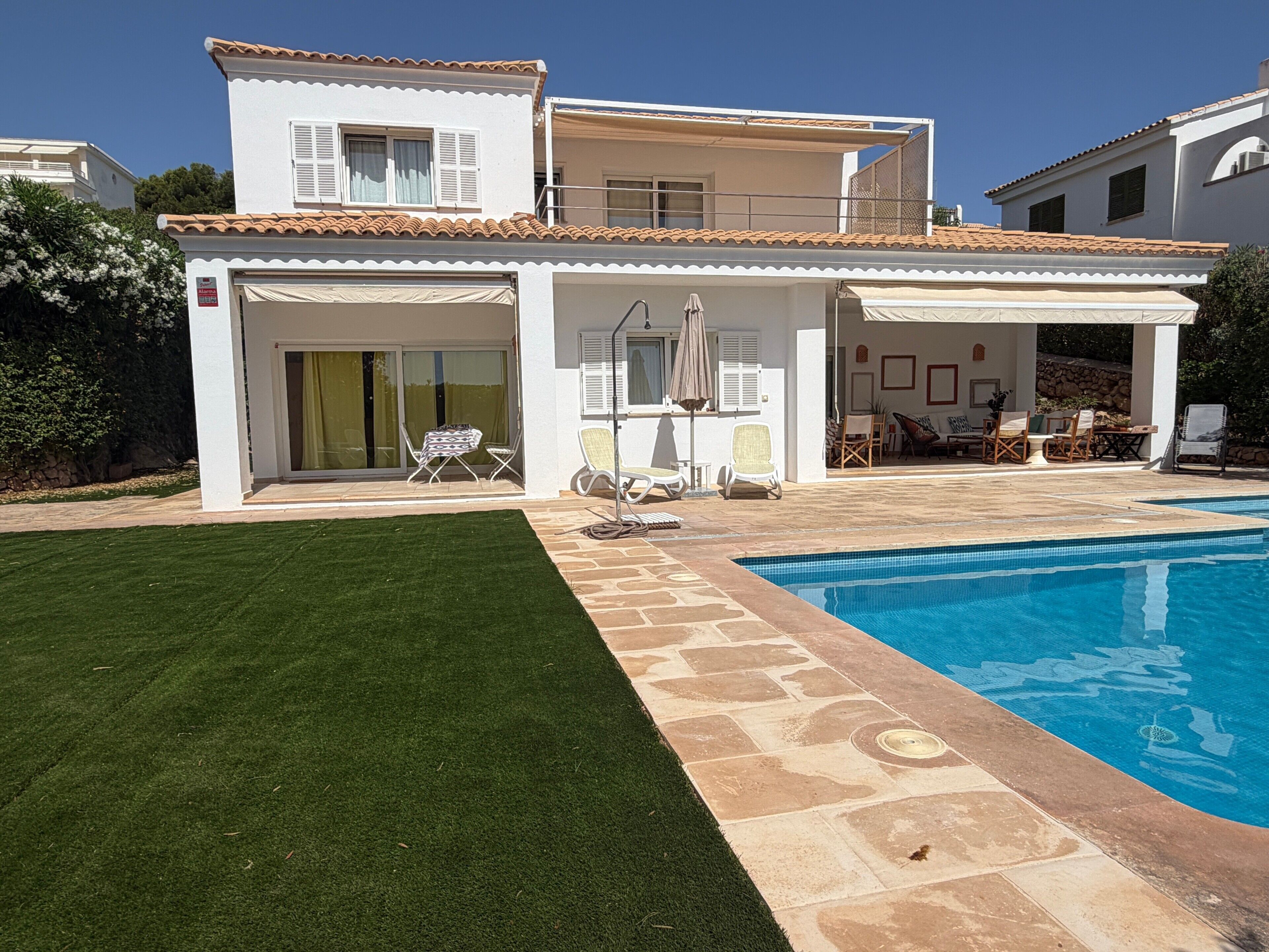 Une maison à deux étages avec une piscine, un patio couvert et une pelouse.